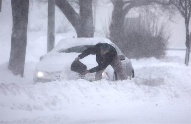 大型冬季風暴襲擊北美。圖為紐約一名男子試圖將汽車「挖」出來。（圖／美聯社）