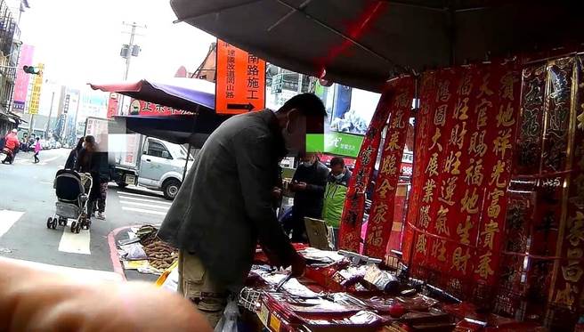 54歲張姓男子因為在岡山文賢市場旁違規擺攤賣春聯，遭警方取締違規設攤，導致通緝犯身分曝光。（翻攝照片／林瑞益高雄傳真）