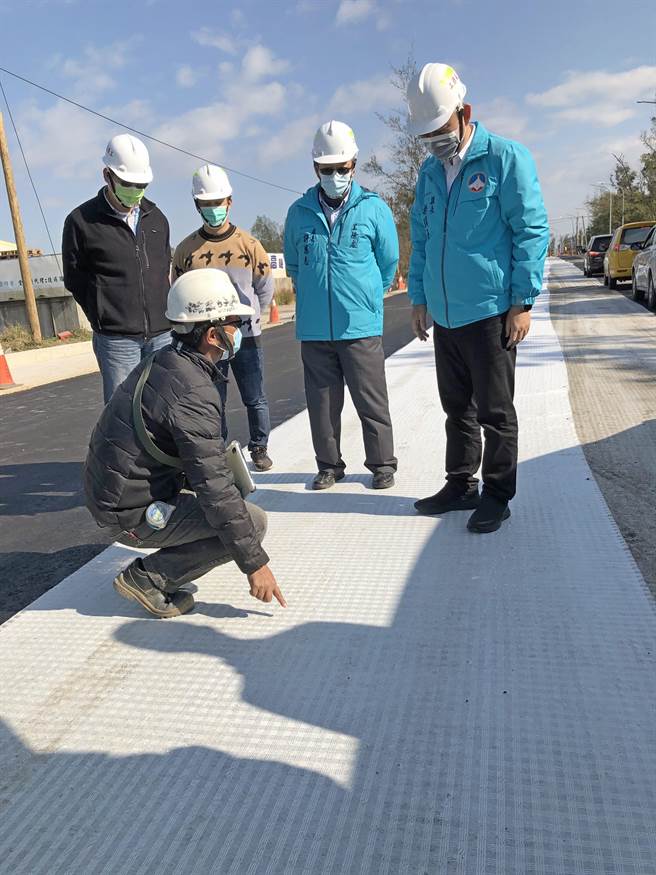 廠商現場說明採用鋪設防裂網工法，可延緩未來路面的裂縫產生。（李金生攝）