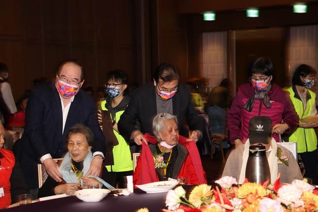 中時--先嗇宮董事長李乾龍（左1）和劉和然（中）為長輩披上圍巾。（新北市社會局提供）