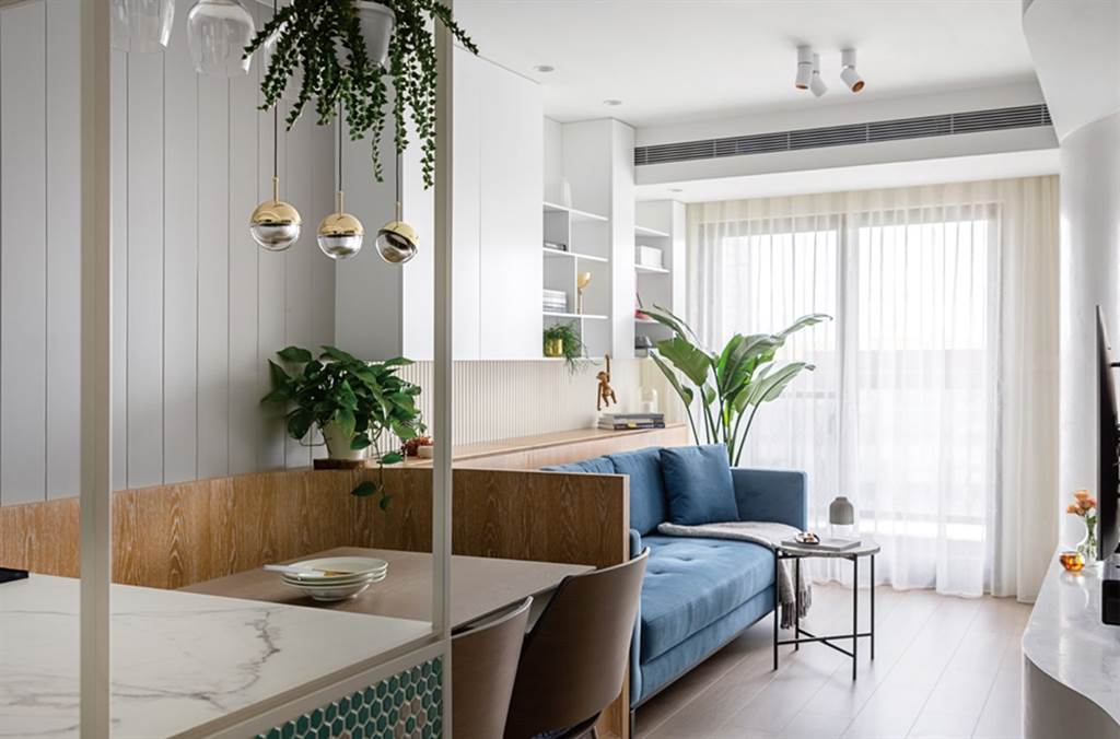 公領域以藍沙發、木背牆與綴飾淺藍馬賽克的白色工作檯，將各機能區自然切分出來。再透過綠植高懸、平擺與落地的層次搭配，連結了大自然色彩與意象，讓家更舒適迷人。（圖片提供／爾聲空間設計）