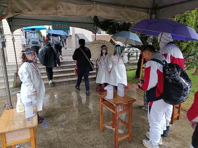 桃園市復旦高中有學生家長確診，全校21日預防性停課，不過復旦高中也是學測考場，一早考生需消毒後入場。（賴佑維攝）