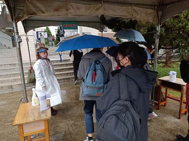桃園市復旦高中有學生家長確診，全校21日預防性停課，不過復旦高中也是學測考場，一早考生需消毒後入場。（賴佑維攝）