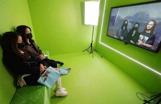 图为展场中的「蒙宇宙」，利用人工智慧使蒙娜丽莎人物仿似復活，餐与者坐在绿幕背景前即可穿越时空，进入蒙娜丽莎画作的三度空间，和女主角合影。（季志翔摄）