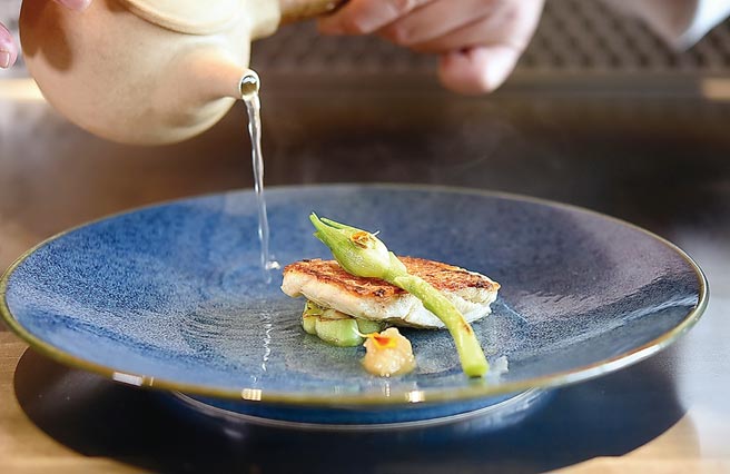 〈季节鲜鱼〉是将鱼肉香煎后，搭配台南西瓜绵熬制的鲜鱼汤汁提味，并以花莲晚香玉笋点缀呈盘。图／姚舜