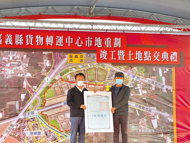 嘉义县长翁章梁（左）将货物转运中心土地权状交给重划区配发土地地主代表萧金狮（右）。（张亦惠摄）