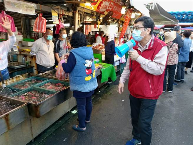 经发局副局长高镇远（右一）昨（23）假日前往兴达港观光渔市宣导防疫，手持大声公逐摊提醒摊商及民眾落实防疫。。（柯宗纬翻摄）
