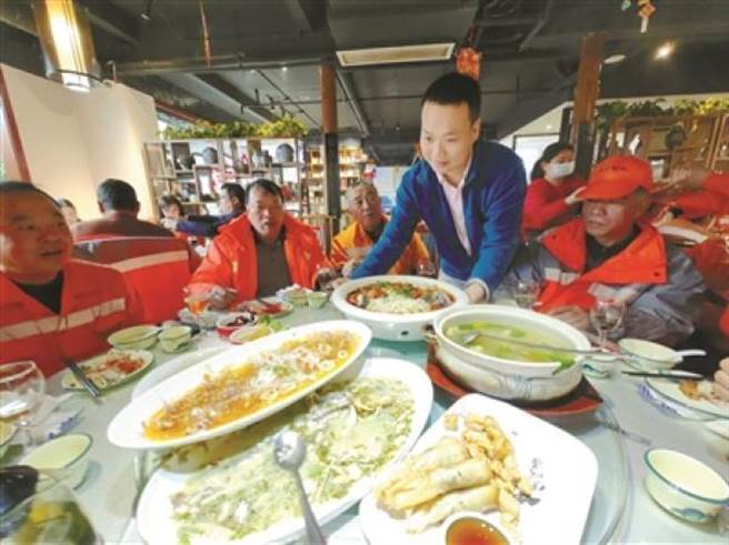 寧波餐馆第7年请清洁员吃年夜饭：每桌8700元上龙虾 。图为王玉乐给清洁员上菜。（中国寧波网）