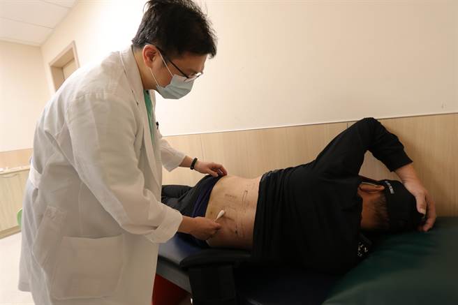 亚洲大学附属医院脊椎暨疼痛治疗中心、骨科部主治医师林琮凯为患者检查伤口。(林欣仪摄)