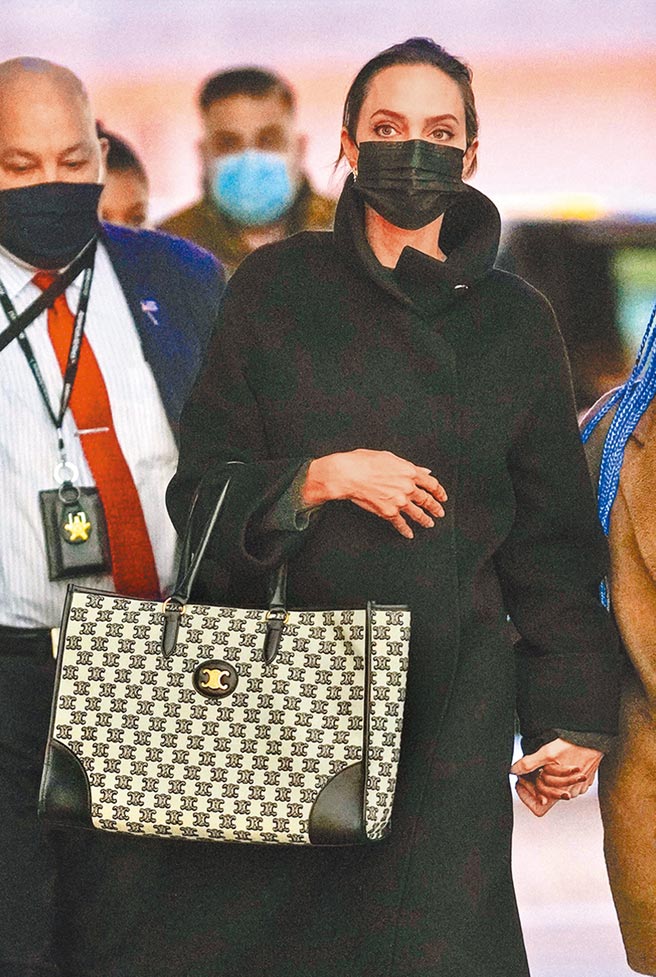 安洁莉纳裘莉身穿黑色大衣，搭配CELINE TRIOMPHE EMBROIDERY黑色凯旋门经典花纹横式托特包，打造穿搭亮点。（CELINE提供）