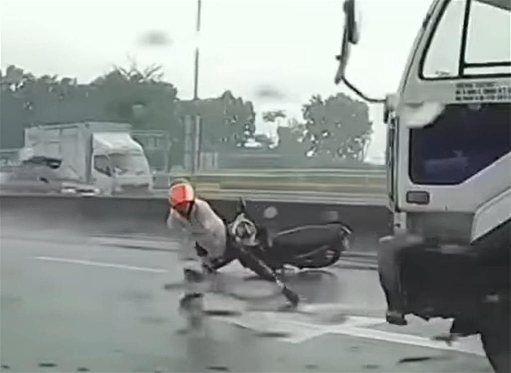 一名騎士雨中在內側車道自摔，但他卻使出瞬間脫逃術，迅速爬起後，2秒內連續躲過後方高速經過的自小客，及大貨車逃到路旁逃命，險遭到輾過。(翻攝臉書社團「八卦村 - 行車紀錄器影片上傳中心」）