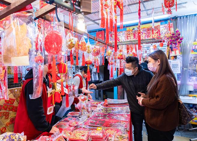 农历新年即将到来，虽然近日本土疫情升温，在小年夜仍有许多民眾上街办年货，忙着採买春联等春节饰品，准备带回家布置。（罗永铭摄）