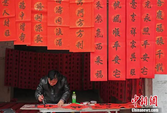 2022年1月，在广西融水苗族自治县汪洞乡，一名书法爱好者正写春联。（图/中新社）