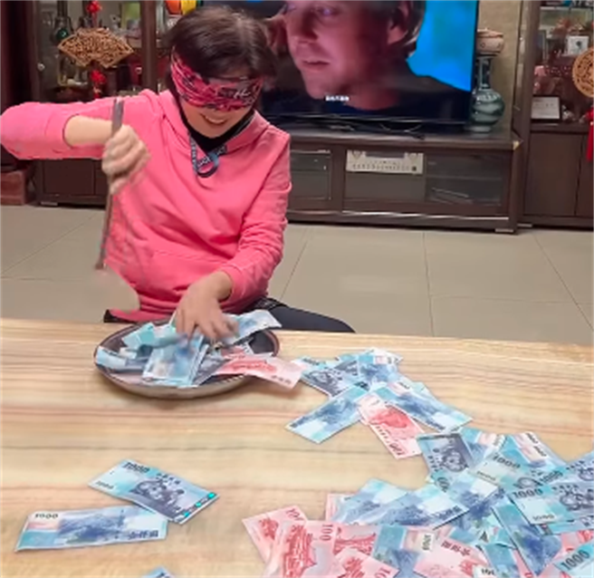 1名网友被母亲抱怨今年红包不够多，就将整整13至15万的钞票洒满整桌，让母亲矇眼拿锅铲铲，铲到多少、红包就是多少。（翻摄自脸书「爆废公社」）