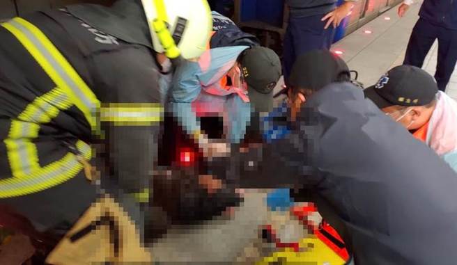 林妇被救护人员从坠落的轨道上救出，所幸仅受轻伤。（翻摄照片／石秀华高雄传真）