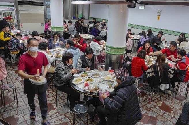 金山老街挤满人潮，民眾涌入知名美食店家品尝佳肴，由于店家厨房与餐席分离，饕客端着菜肴穿梭人群中前往老街多处店面享用，店内座无虚席。（黄子明摄）