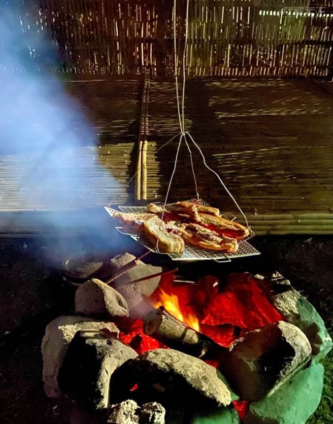 坐在猎寮前享用原民风味炭火烤肉，满满的风味。(图/行遍天下)
