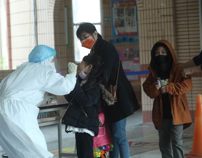 本土疫情持续升温，目前国内12岁以下本土个案共有82人，逾6成有发烧情形。图为小学生进行採检。（本报系资料照）