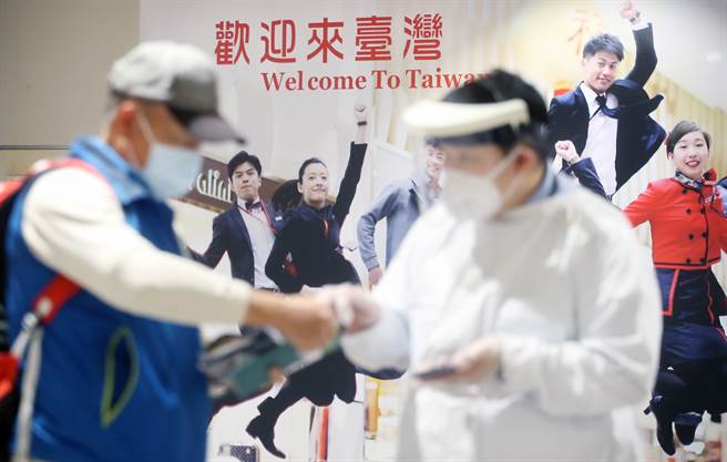 在桃園機場第二航廈外，剛入境的旅客排隊搭乘防疫計程車，前往防疫旅宿或集中檢疫所。（范揚光攝）