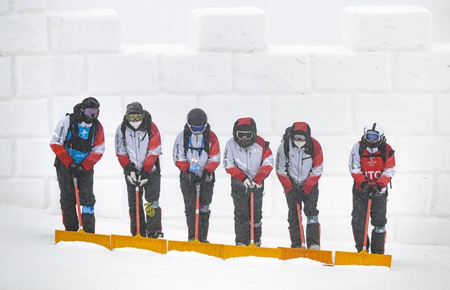 北京13日下起大雪，气象台发出暴雪黄色预警，大雪造成部分冬奥赛事延期。图为冬奥工作人员13日在赛事场地清雪。（新华社）