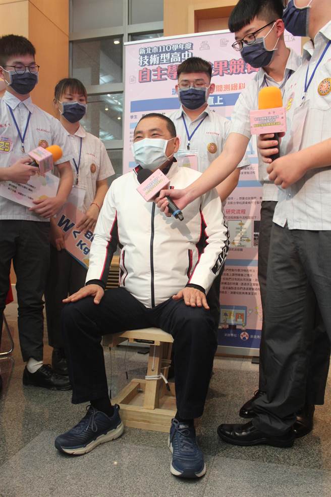 新北市长侯友宜坐在瑞芳高工同学开发制作的「扶摇直上椅」，了解学生创作理念。（陈慰慈摄）