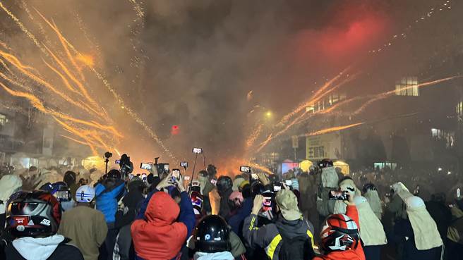 台南盐水蜂炮晚间开炸，火光照亮盐水夜空，群眾纷纷拿着手机、相机抢拍。（张毓翎摄）
