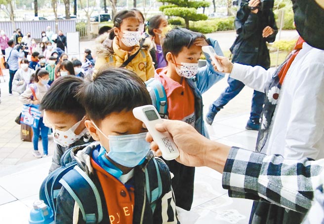 高雄市國小14日開學，由於高雄仍有新確診個案發生，各校不敢大意，老師在門口協助學童落實防疫。（中央社）