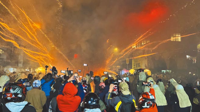 台南盐水蜂炮昨晚定点施放，火光照亮盐水夜空，群眾纷纷拿着手机、相机抢拍。（张毓翎摄）