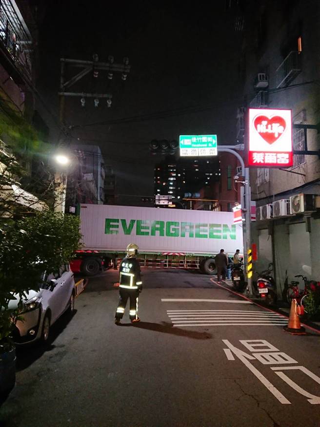 今晚(17日)一輛長榮貨櫃車卡在三重巷弄內動彈不得，疑為司機未注意限高，導致貨櫃卡死電線桿天線。(圖／讀者提供)