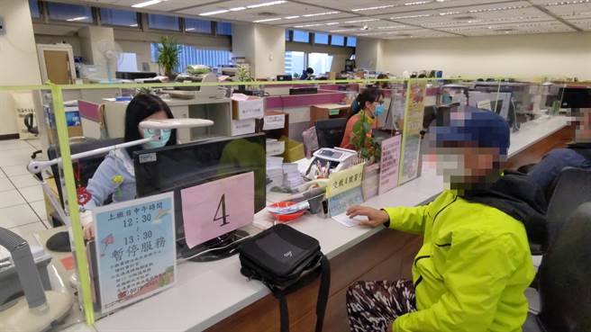 59歲高姓男子（右）至新北市政府交通事件裁決處服務窗口以現金繳清9萬元罰鍰。（新北分署提供）