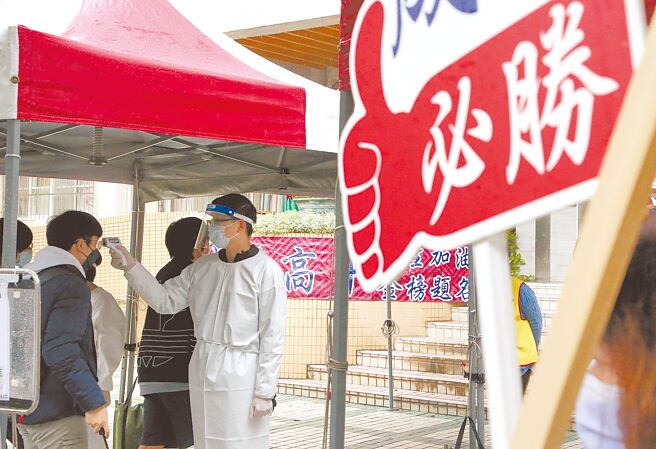 新冠肺炎疫情也入学测考题，民眾对自然科第25题答案虽有疑问，但大考中心决定不送分。图为今年1月21日在台北市成功高中学测考场，考生进入试场前必须先量体温。（本报资料照片）