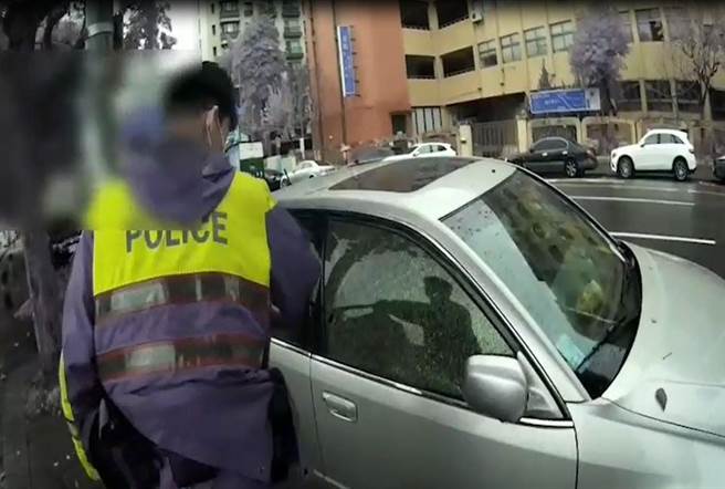 员警以警棍将副驾驶座车窗玻璃击破，救出女童。（翻摄影片）