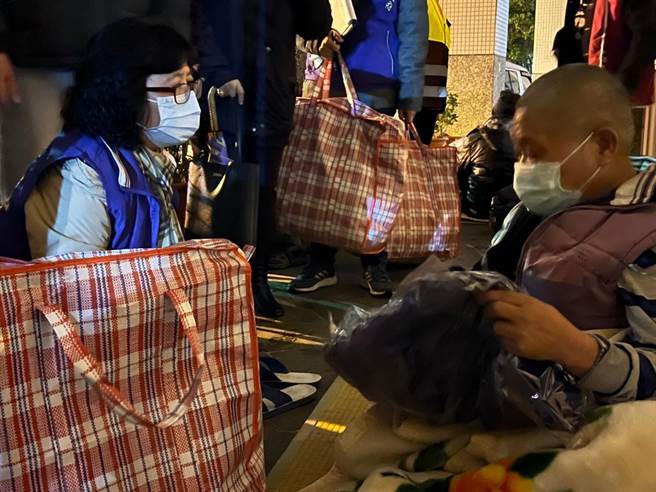 許秀能送禦寒衣物給在四維公園露宿的阿榮，力勸他入住安心旅館或中途之家。（新北市社會局提供）