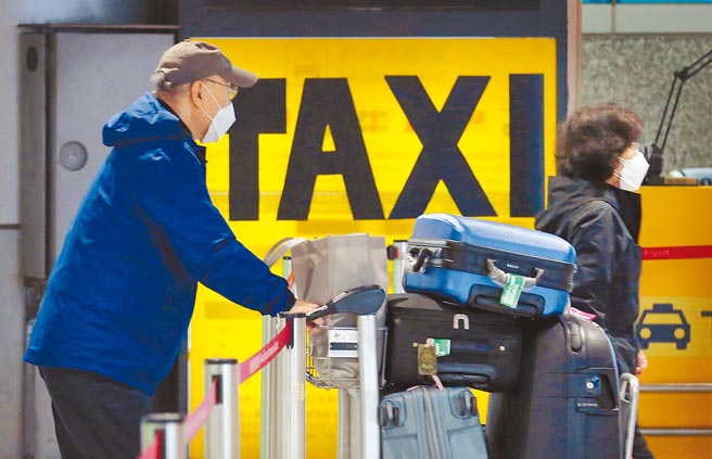 WHO建议隔离期可缩短，台湾目前仍维持14天。图为桃园机场第二航厦外，刚入境的旅客搭乘防疫计程车前往防疫旅宿或自费集中检疫所。（范扬光摄）