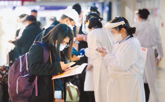 中央流行疫情指挥中心19日公布新增8例本土个案及65例境外移入。图为在桃园机场入境管制区内，防疫人员协助旅客登录入境检疫凭证。（范扬光摄）