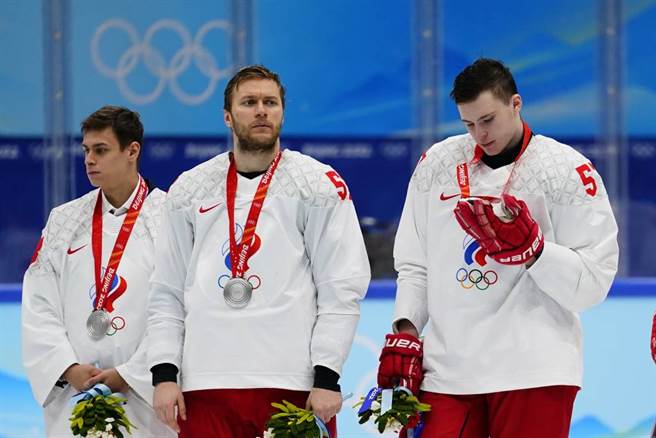 北京冬奥ROC男子冰球队Alexander Nikishin(右)看着自己的银牌。ROC在决赛败给芬兰。（美联社资料照）