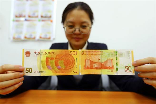 山西太原一銀行內，工作人員展示人民幣發行70周年紀念鈔。（摘自中新社）