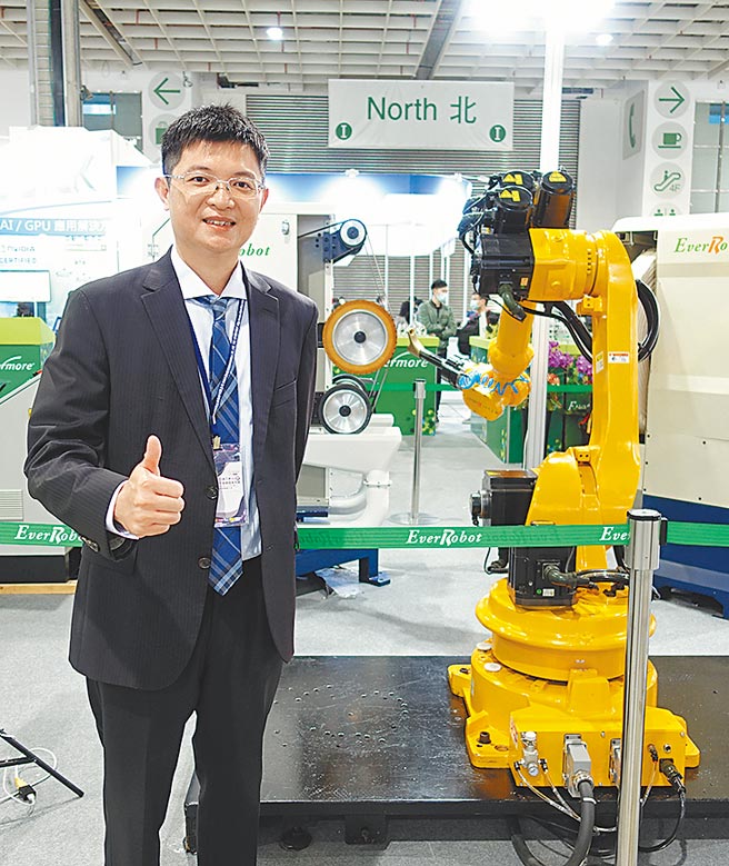 勤堃機械總經理廖河誠，和該公司機械手臂合影。圖／黃俊榮