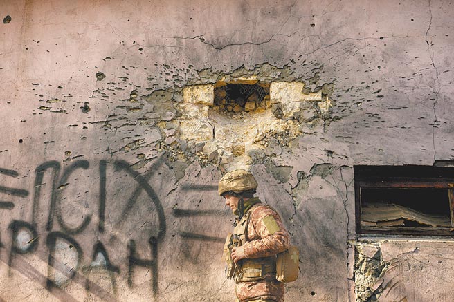 乌克兰军方表示，乌东亲俄分离主义分子发动炮击，图为乌克兰军人行经乌东前线村庄一座被大口径迫击炮弹击中的建筑物。（美联社）