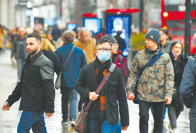 英国首相强生周一将宣布解除新冠患者的隔离要求，英国成为首个容许染疫者无须隔离的欧洲国家。图为一名戴着口罩的购物者走在伦敦的牛津街。（路透）