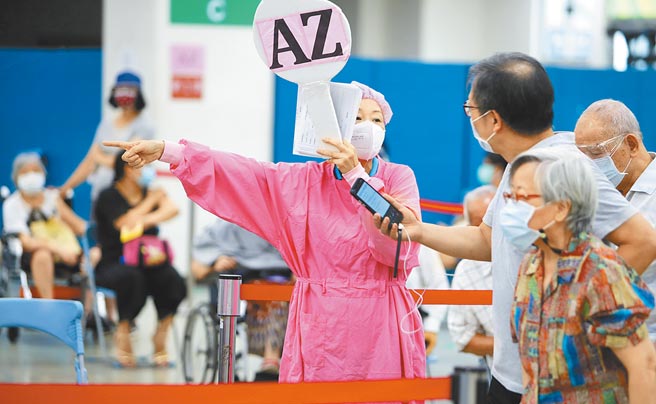 双北20日再新增2例本土确诊案，新北市卫生局说，个案居隔第4天阴转阳对社区几乎没有影响。图为护理师高举写有AZ的牌子指挥民眾入座施打疫苗。（本报资料照片）