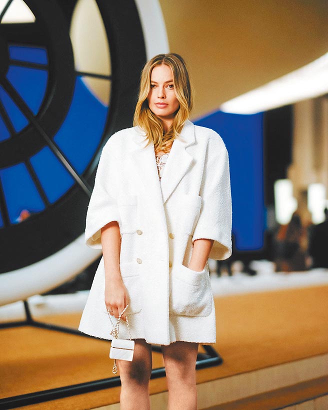 玛格罗比出席香奈儿春夏高订发表会时，即身穿春夏米白金色鉤织洋装外搭米白斜纹软呢外套现身。（CHANEL提供）