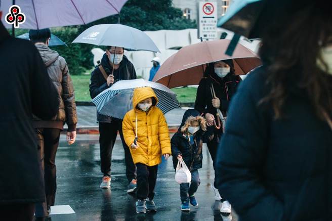 寒流来袭加上下雨，街上行人包紧紧撑着伞前进。（本报资料照片）