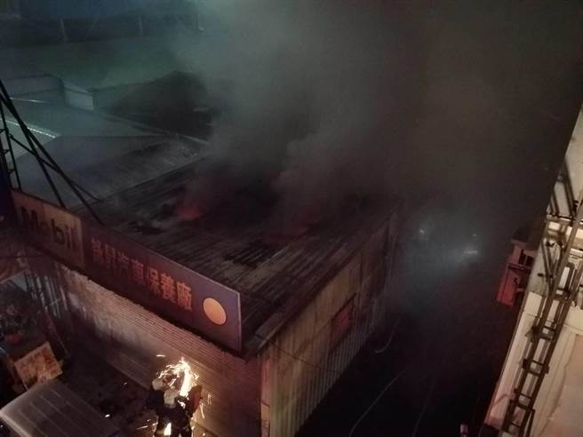 嘉義市一家汽車維修廠大火，火勢初步控制，濃煙仍竄出，消防人員持續搶救中。（讀者提供）