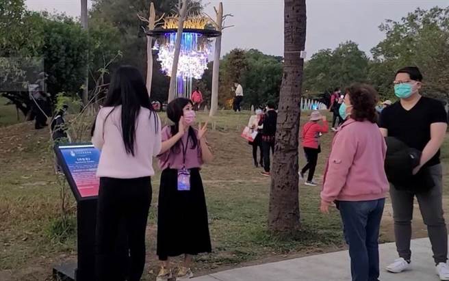 新住民通译志工为民眾讲解新住民灯区的「共生花」作品。（高雄市民政局提供／林瑞益高雄传真）