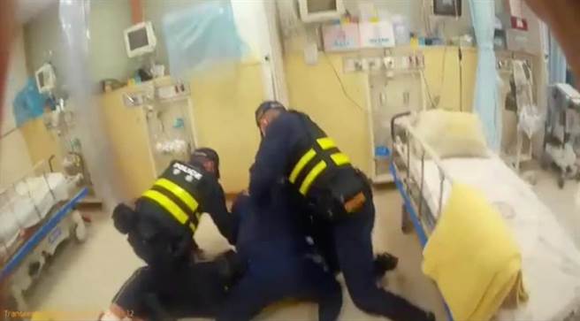 施男到医院再度失控，破坏医院设备，还捶打病床等，最后被警方压制在地上，上铐予以管束。（警方提供／吴建辉南投传真）