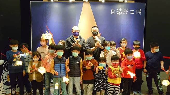小朋友们与青年局局长张以理(后排中间右)、卫武营总监简文彬(后排中间左)一起展示自制小提灯成果。(高雄市青年局提供)