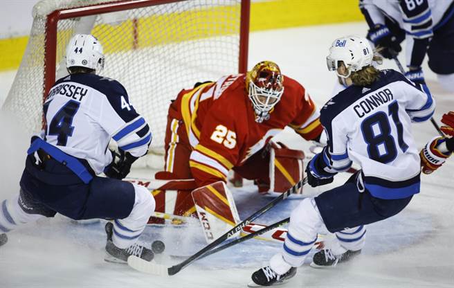 卡加利火焰門將Jacob Markstrom(中)遭到對手夾攻。（美聯社資料照）