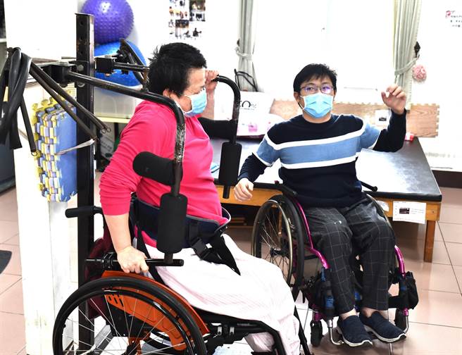 冈山「髓喜家园」专业训练员洪铭辰（右）陪着脊损伤者做復健。（林瑞益摄）