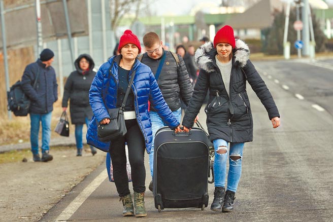 面对俄罗斯军队来袭，靠近与他国边界的乌克兰民眾，纷纷避难。图为乌克兰人步行往邻国匈牙利躲避战火。（路透）